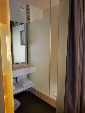 Une salle de bain moderne avec une douche à parois de verre, un lavabo blanc avec un miroir et un porte-serviettes.