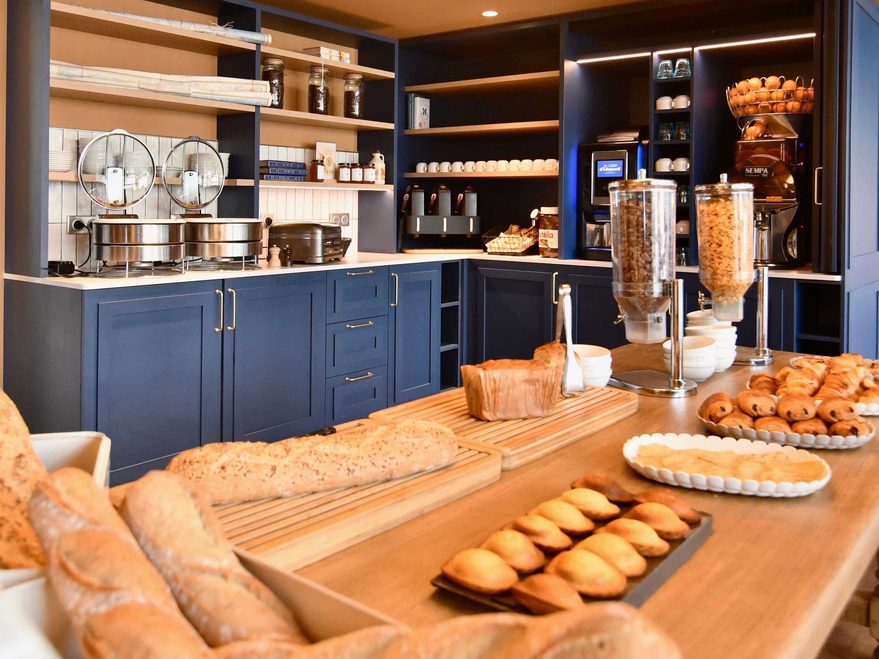 Een keuken met een koffieapparaat, potten en verschillende gebakjes.