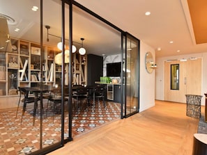 Un intérieur moderne comprenant un coin repas, une cuisine et un espace de vie agrémenté d’un grand miroir et de portes coulissantes.