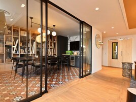 Un intérieur moderne comprenant un coin repas, une cuisine et un espace de vie agrémenté d’un grand miroir et de portes coulissantes.