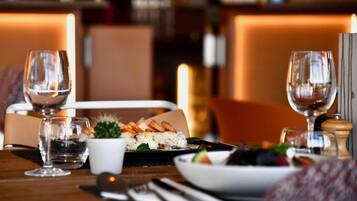 Una mesa lista para comer con sushi, una ensalada y dos copas de vino.