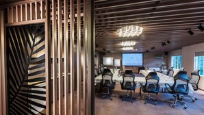 A modern conference room with a long table, black chairs, and a large screen. - Eltham Gateway Hotel (Eltham)