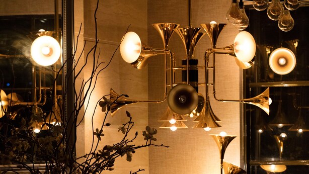 A room with a dark wooden cabinet, a vase with branches, and multiple floor lamps with exposed bulbs. - Eltham Gateway Hotel (Eltham)