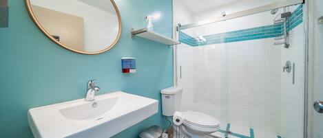 A bathroom with a sink, toilet, and glass shower enclosure.