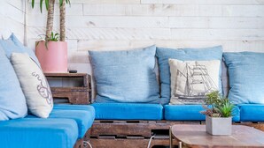 Un coin salon accueillant avec un canapé bleu, des caisses en bois et une plante en pot.