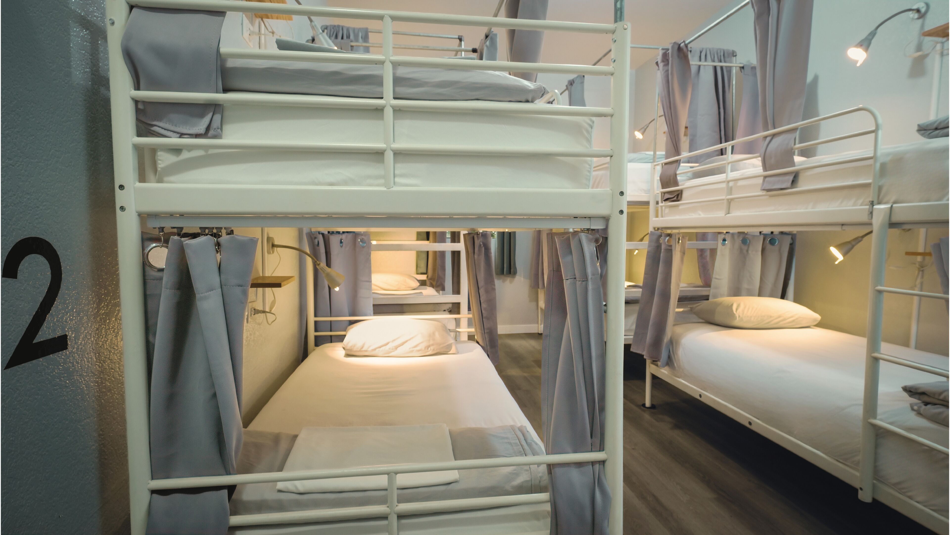 A bunk bed room with a number '2' on the wall, a bedside table, and a lamp.