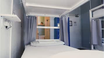 Una habitación pequeña con una litera, una mesita y una ventana con cortinas.