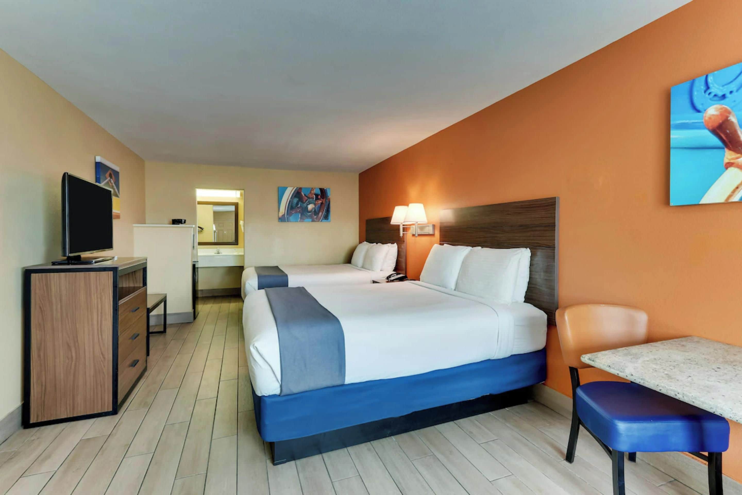 Una habitación de hotel con una cama, un escritorio, una silla, un televisor y un baño.