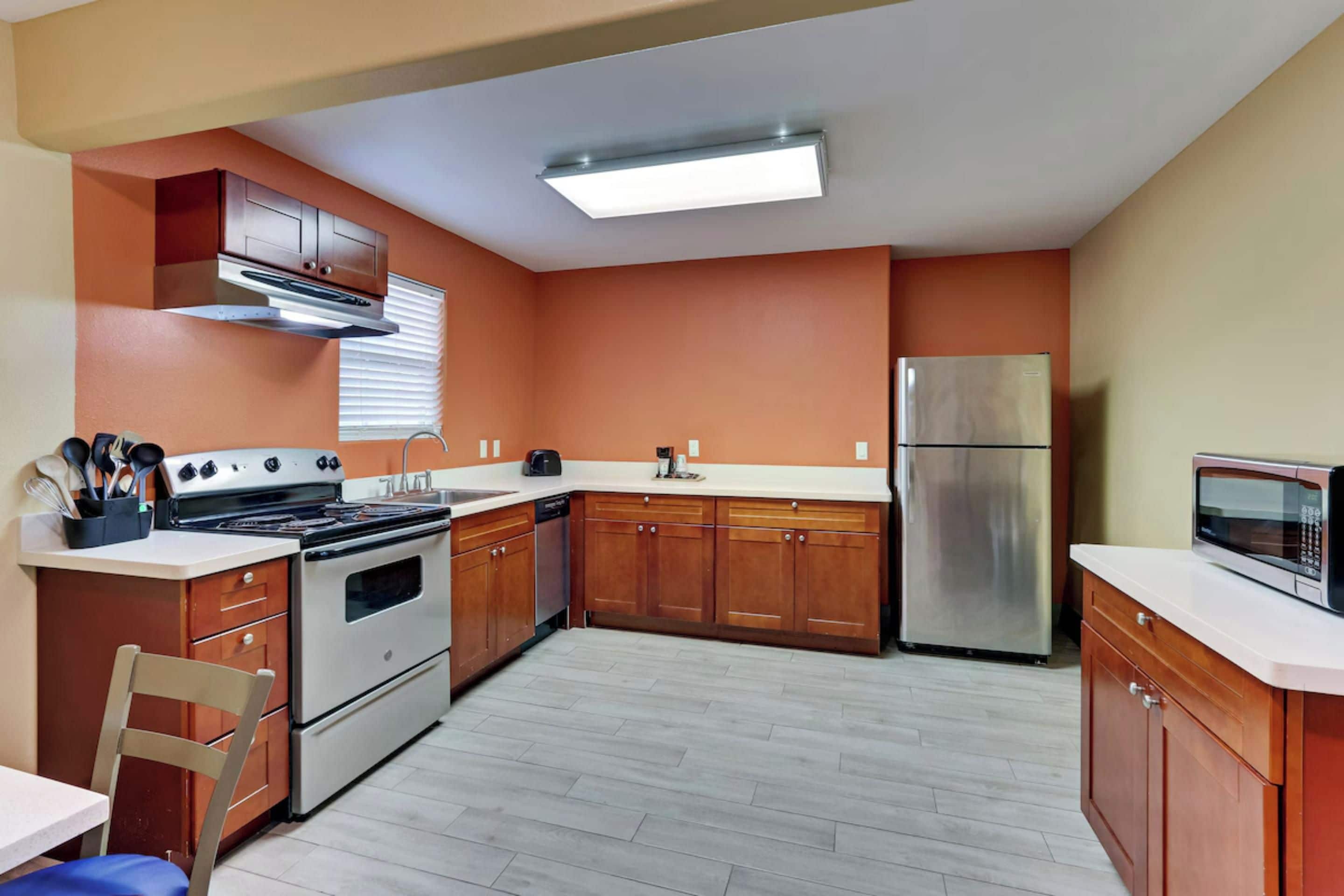 Una cocina con armarios de madera, un refrigerador de acero inoxidable, un microondas y una estufa.