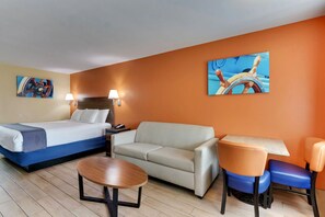 A hotel room with a bed, a sofa, a table, and two chairs. - Captains Quarters Inn Port Aransas TX (Port Aransas)