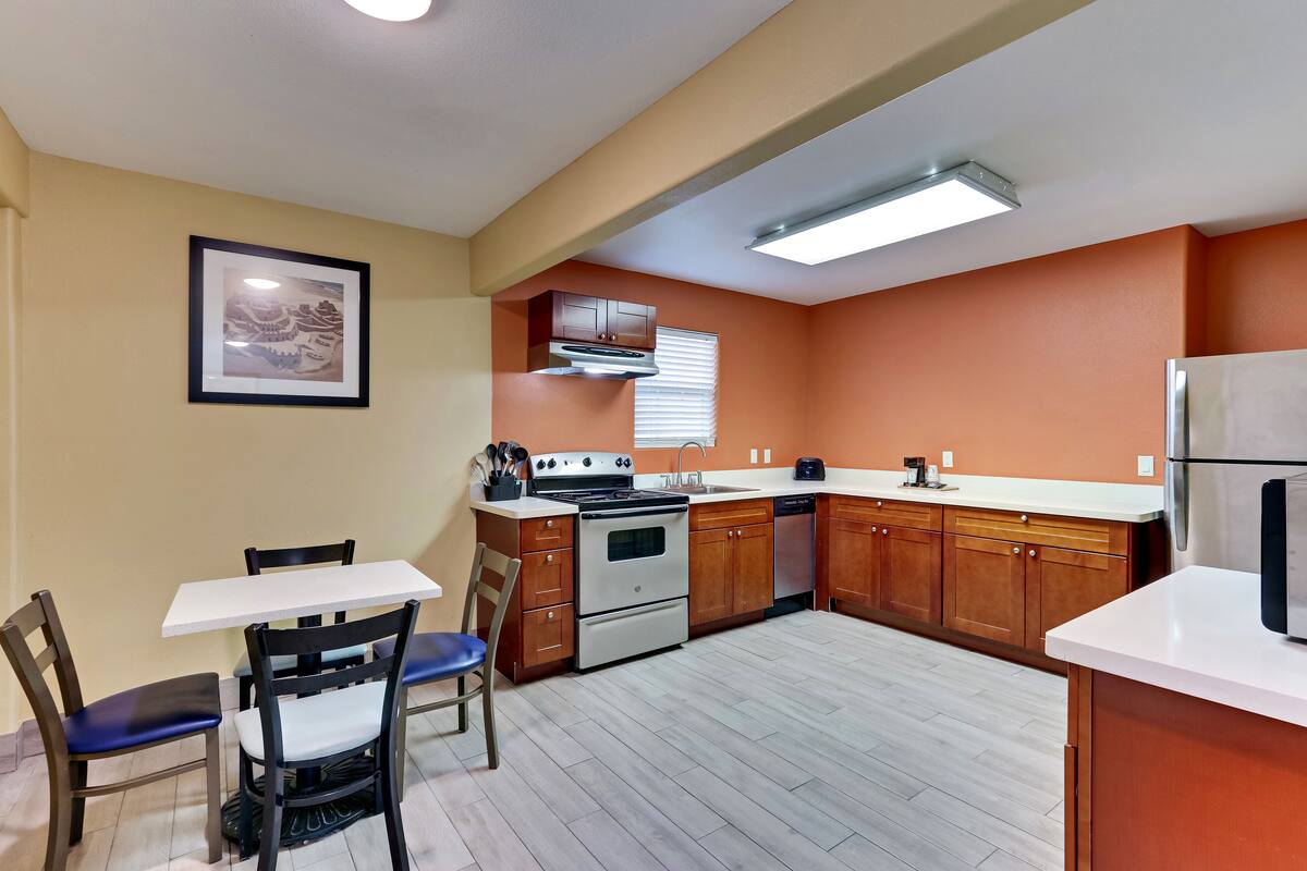 A compact kitchen with a dining area, featuring a stove, oven, and modern appliances.