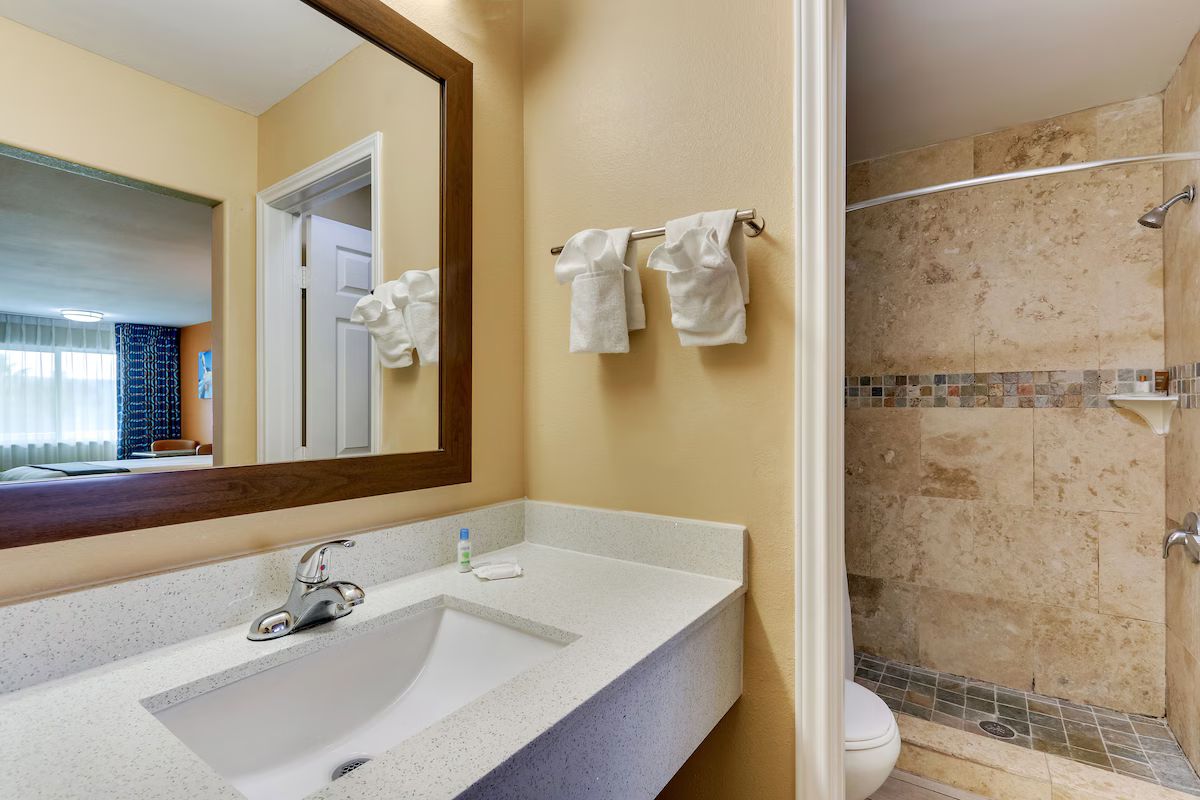 A bathroom with a sink, mirror, and shower.