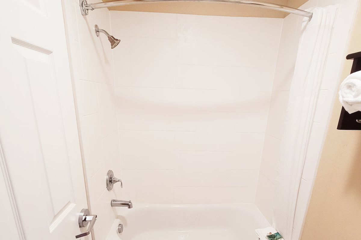 Un baño con ducha, inodoro y un perchero para toallas.