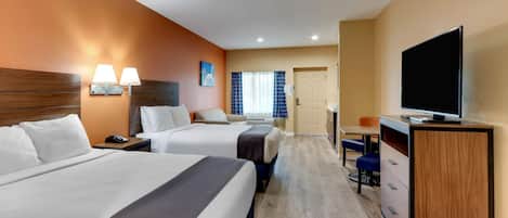 A hotel room with two beds, a desk, a television, and a door leading to a bathroom.