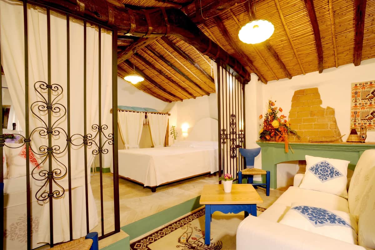 A traditional room with a bed, a sofa, a small table, and a decorative wall piece.