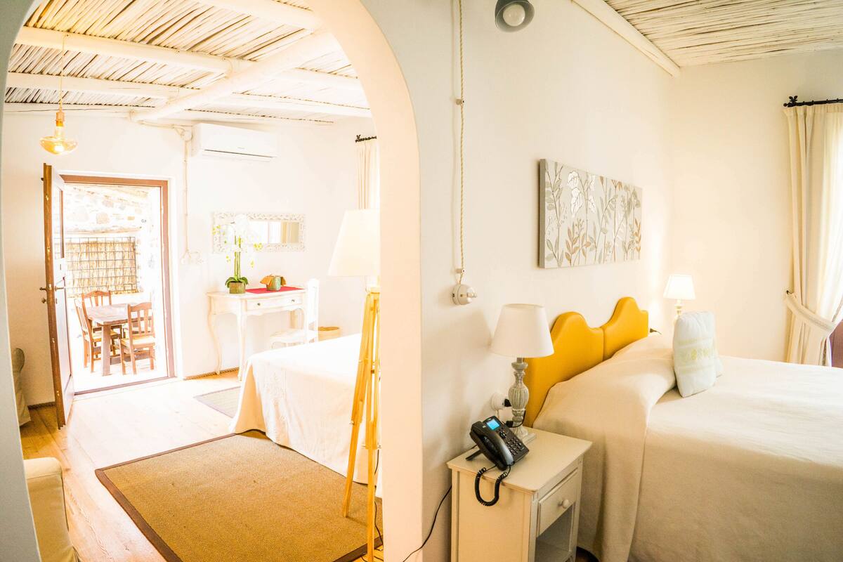 A hotel room with a bed, bedside table, lamp, and a painting on the wall.