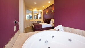 Un baño moderno con una bañera grande, una cama con cabecera marrón y un espejo sobre la cama.