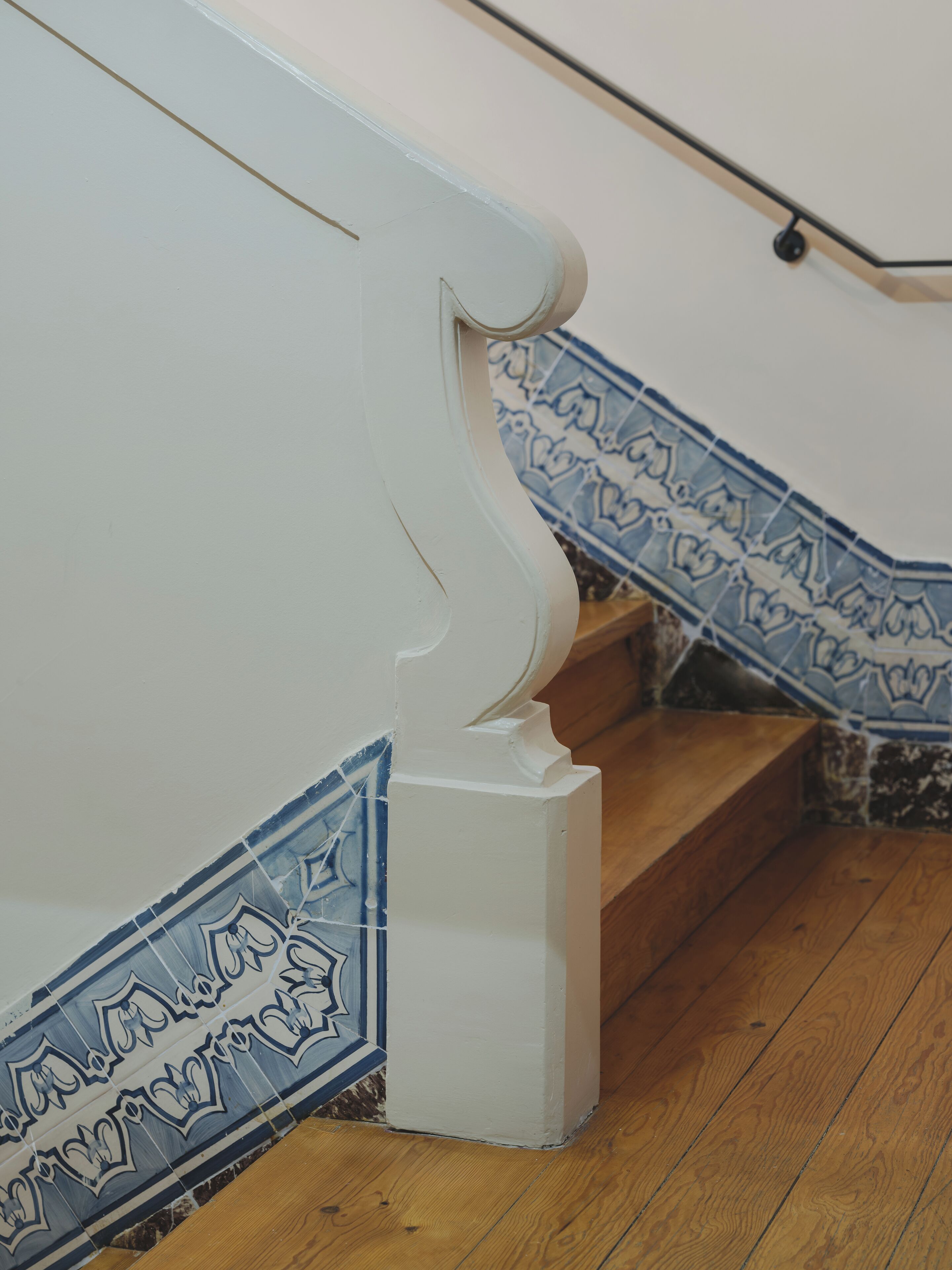 A staircase with white handrails and blue patterned tiles.