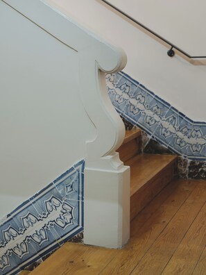 Eine Treppe mit weißen Geländern und blau gemusterten Fliesen.