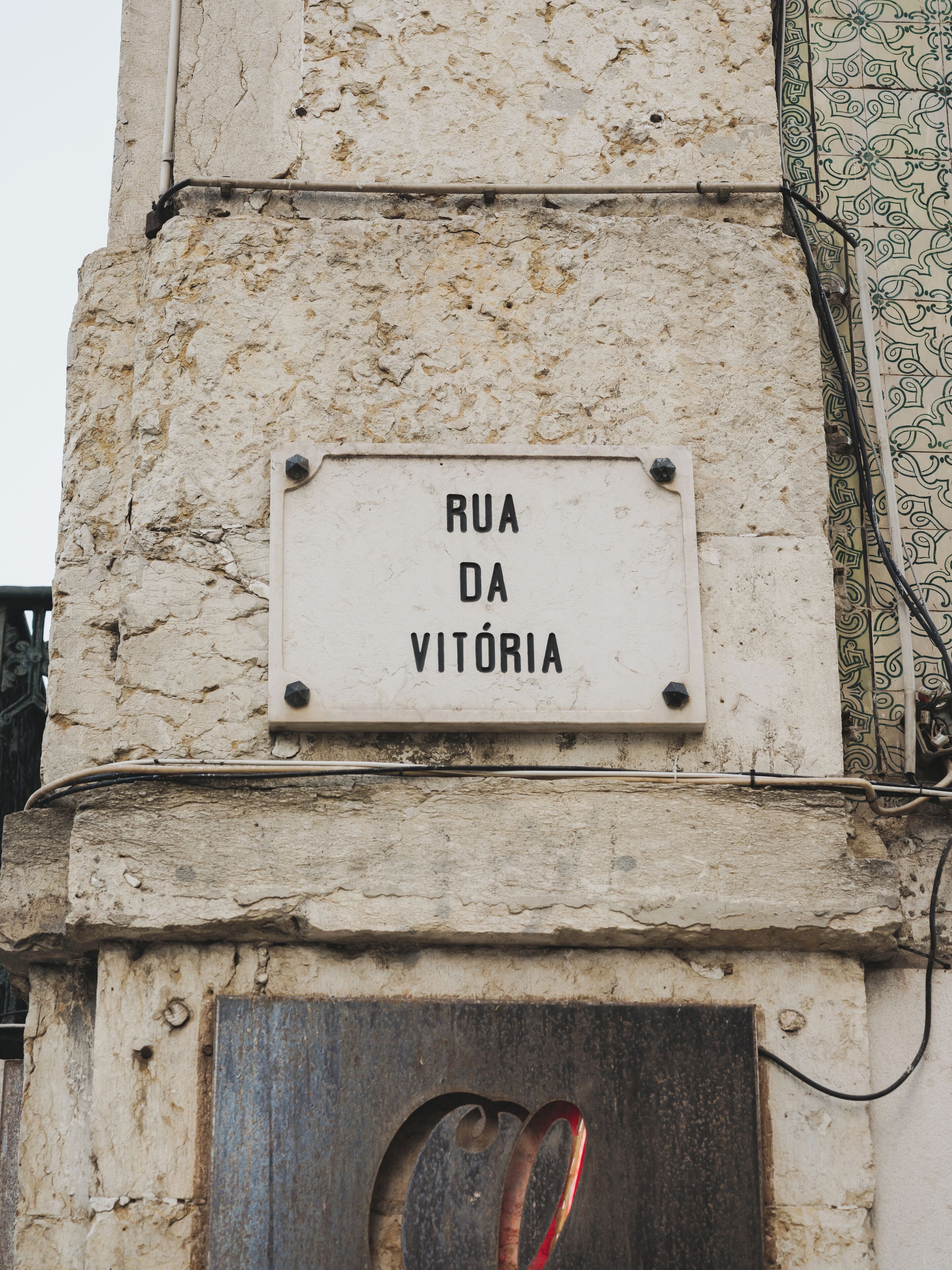 A sign reading "Rua da Vitória" mounted on a stone wall.