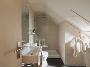 Ein modernes Badezimmer mit einer Duschkabine, einem weißen Waschbecken und einer Toilette.