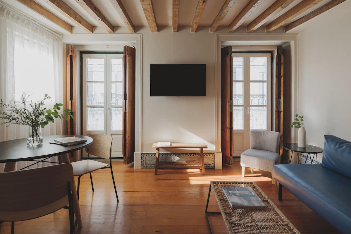 Un salón amplio con suelos de madera, un sofá, una mesa y sillas.