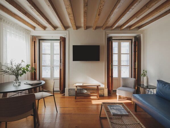 Ein geräumiges Wohnzimmer mit Holzböden, einer Couch, einem Tisch und Sesseln.