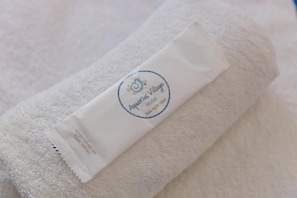 A white towel with a logo and text indicating it is from Aquarius Village Hotel. - Aquarius Village Agistri (Agistri)