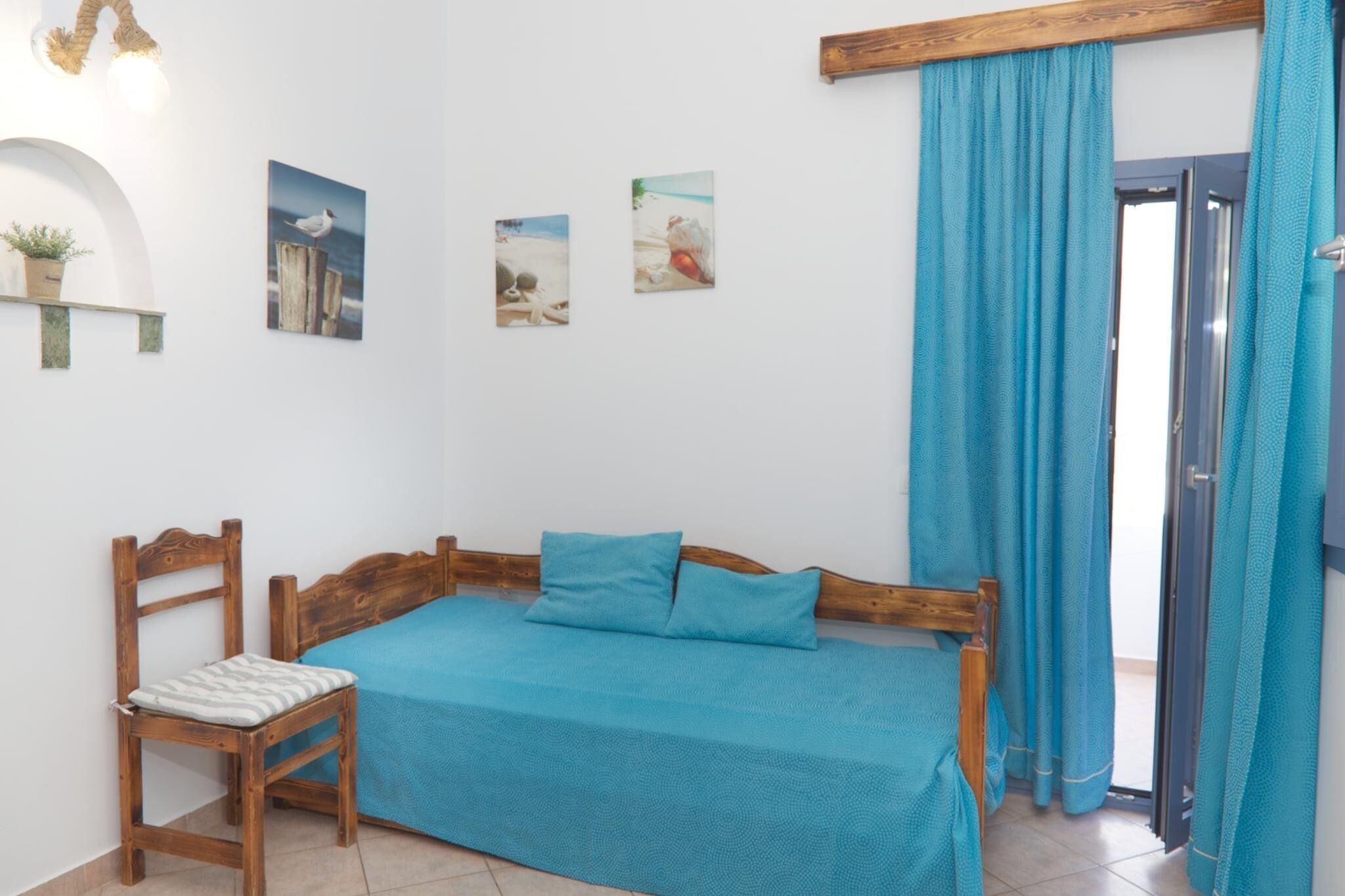 A room with a wooden bed, a wooden chair, and a small table with a plant.