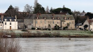 A historic stone building with multiple windows and a large entrance, situated by a river. - Le Relais Louis XI (Meung-sur-Loire)