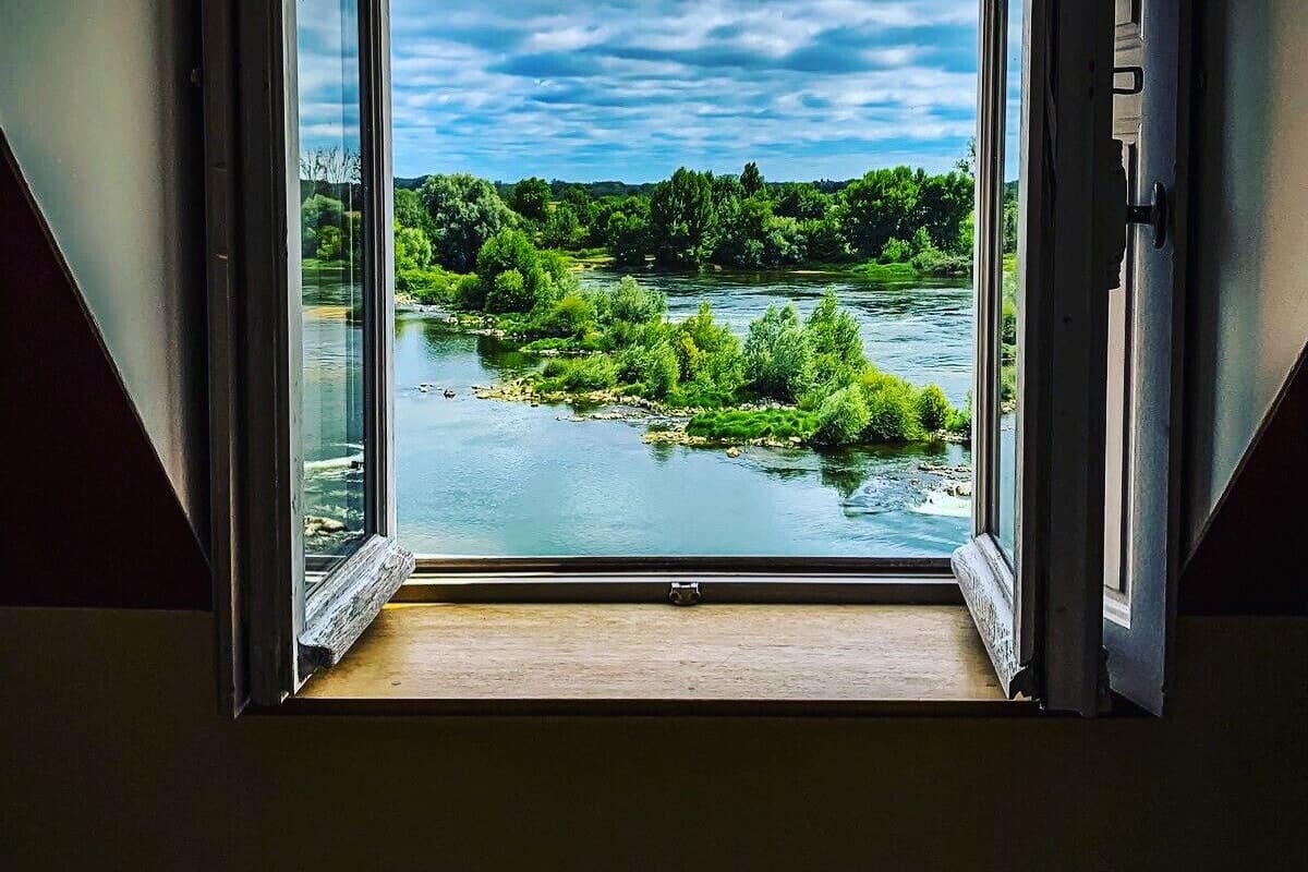 An open doorway with a view of a river and greenery.