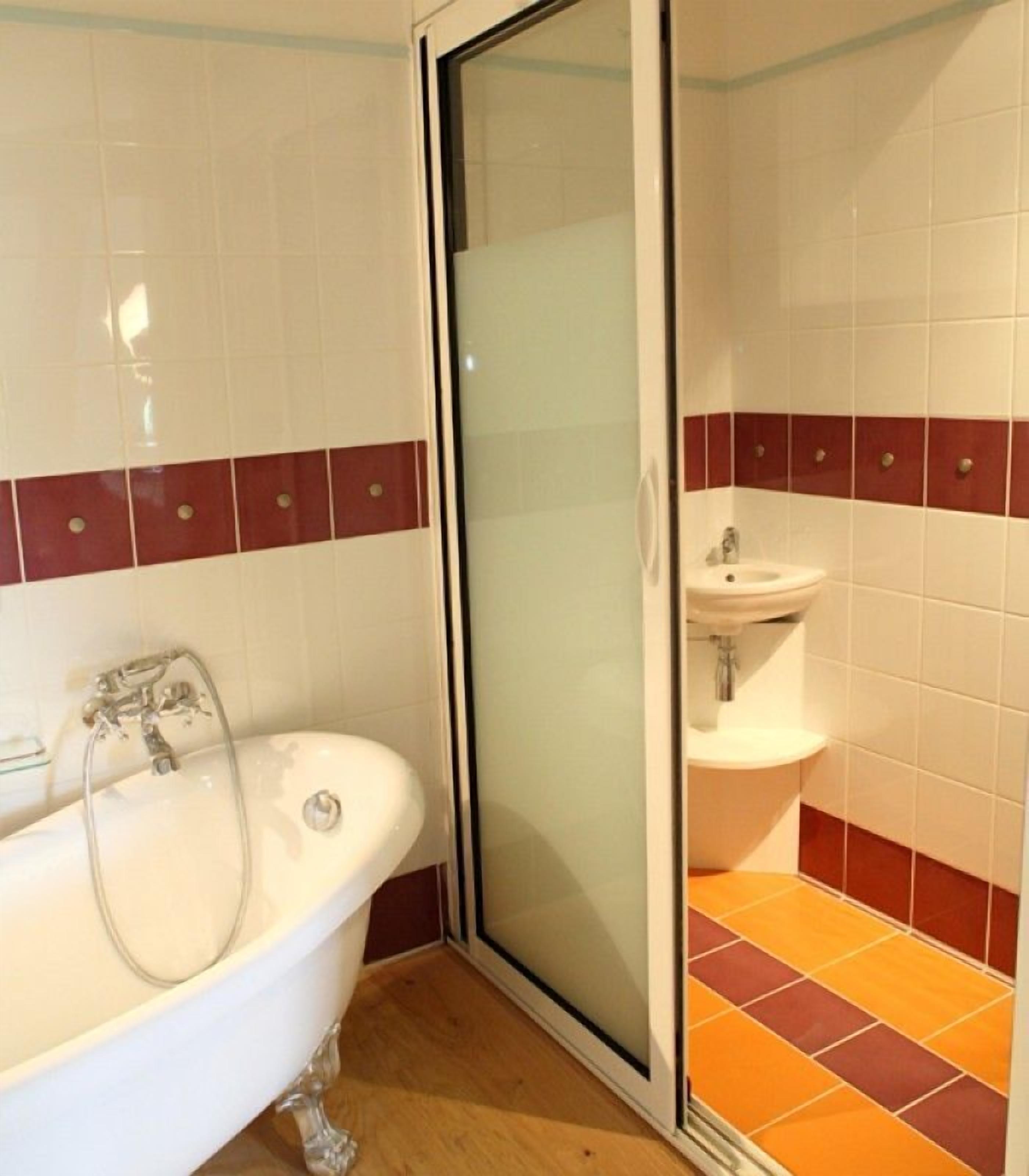 A bathroom with a bathtub, a glass shower enclosure, and a sink.