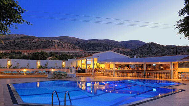 A swimming pool with a bar area and seating, surrounded by mountains.