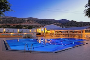 A swimming pool with a bar area and seating, surrounded by mountains. - Melissa Apartments, Studios & Suites (Hersonissos)