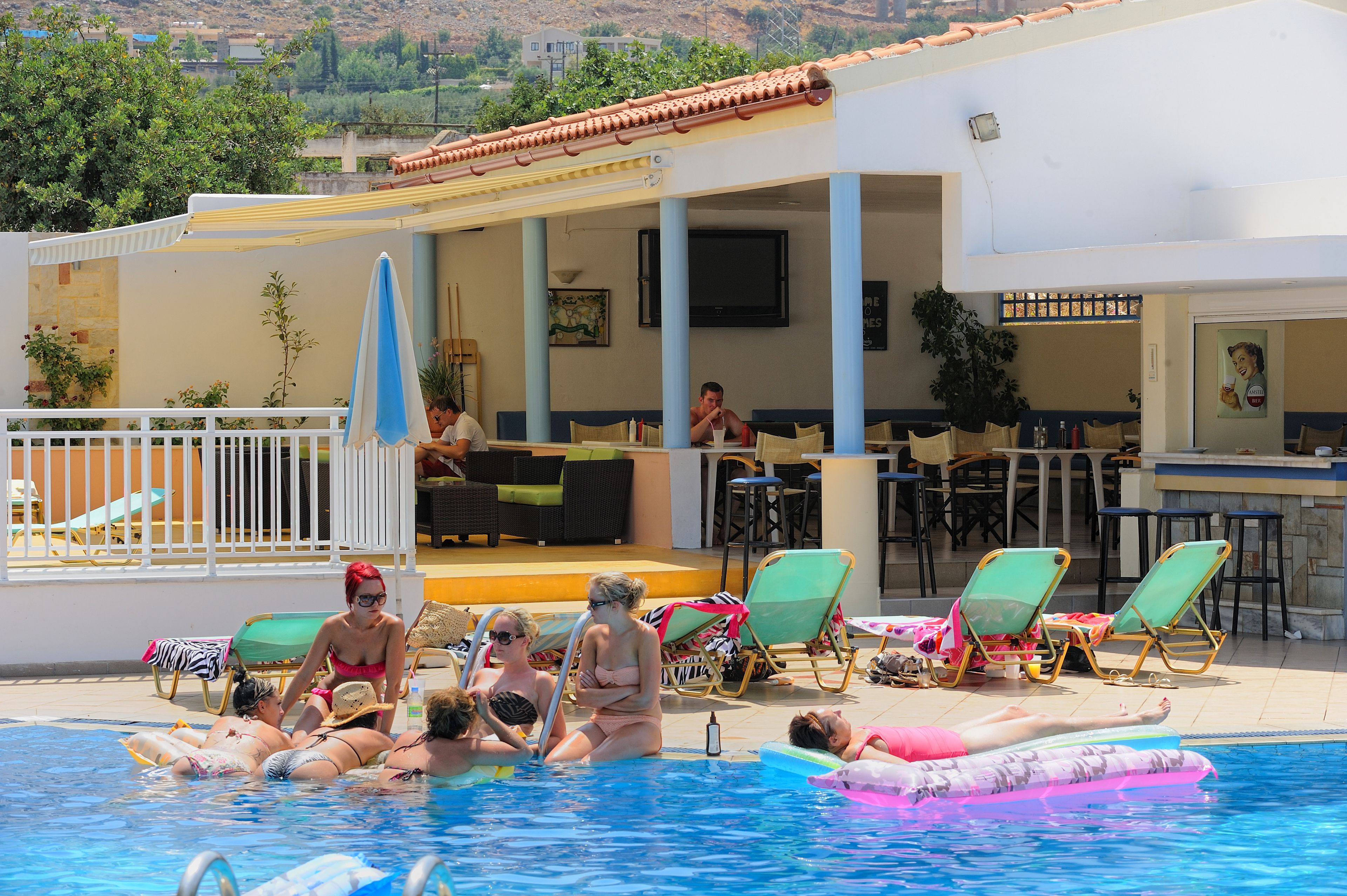 A pool area with lounge chairs, a bar, and a covered seating area.