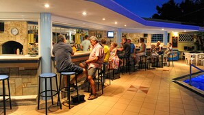 A bar area with stools and a pool.