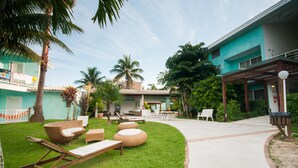 Een resort binnenplaats met buitenmeubilair, palmbomen en een gebouw met een blauwe gevel.