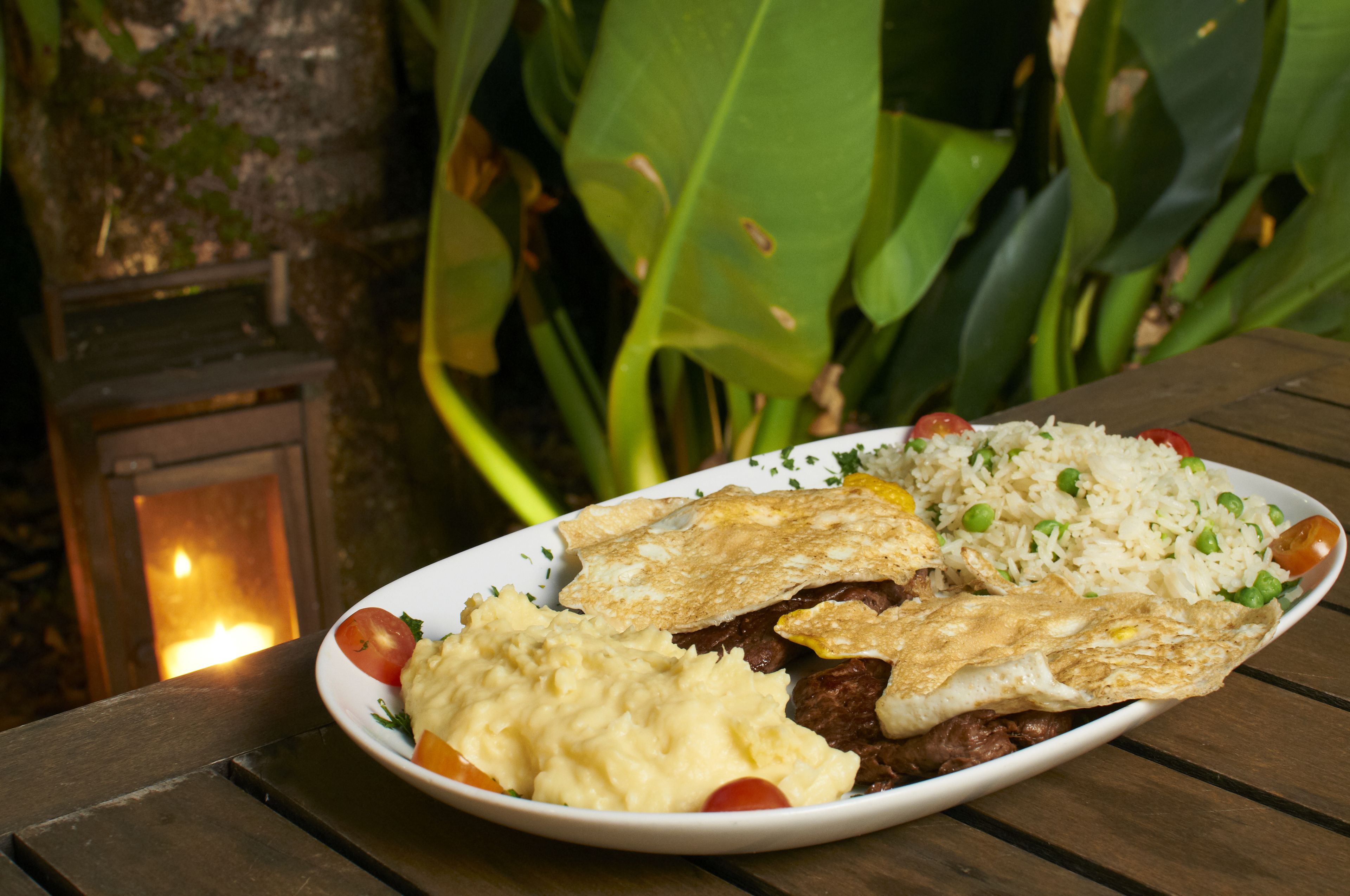 A plate of food on a wooden table with a lit candle in the background.