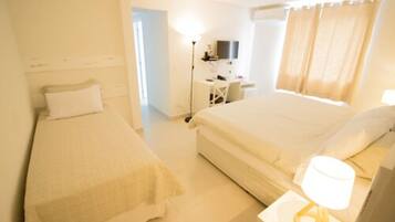 A hotel room with two beds, a desk, a chair, a lamp, and a TV.