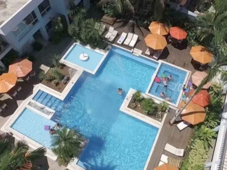 A large outdoor swimming pool with multiple lanes, surrounded by lounge chairs and umbrellas.