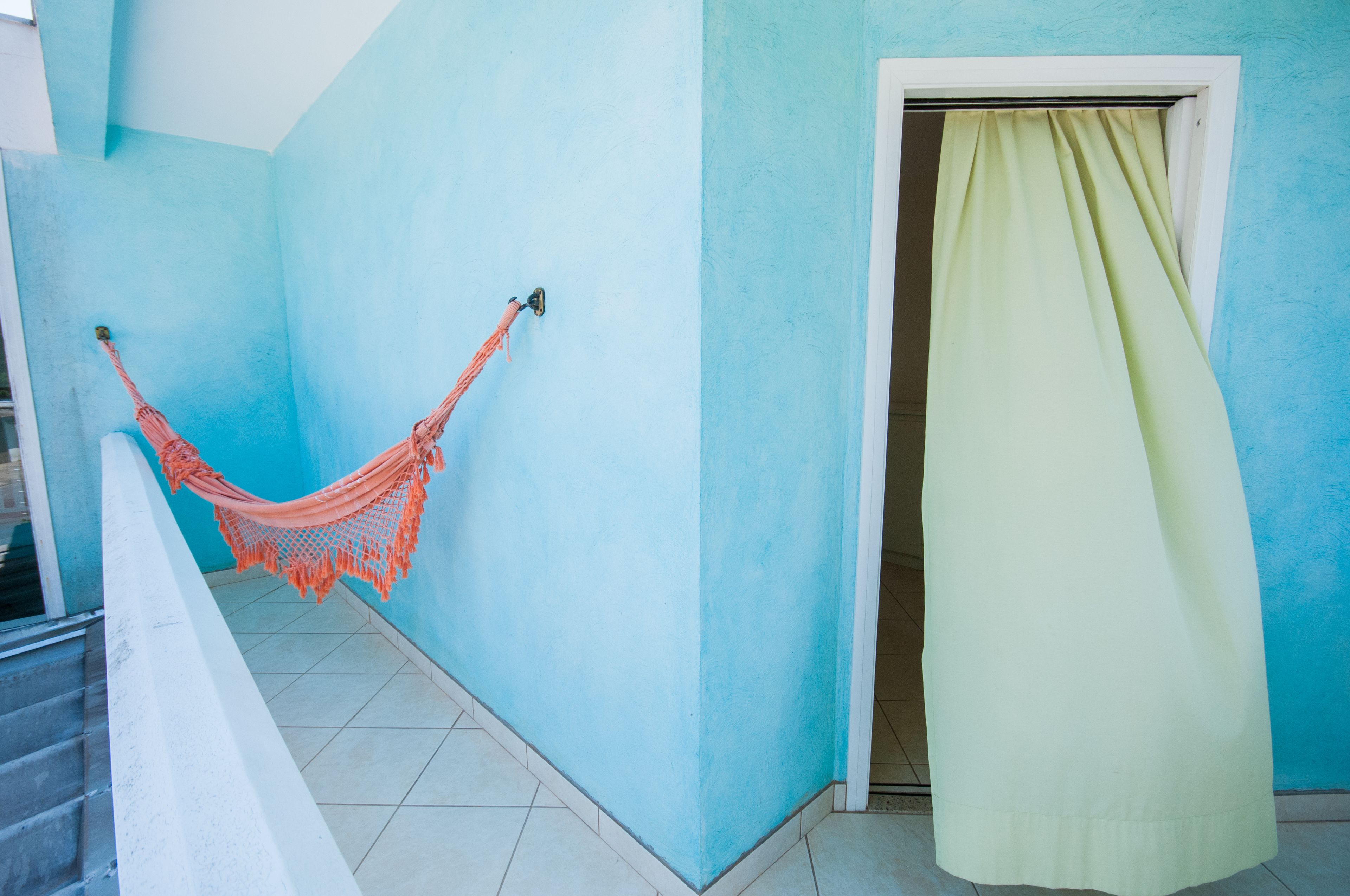 A room with a hammock, a door with a green curtain, and a blue wall.
