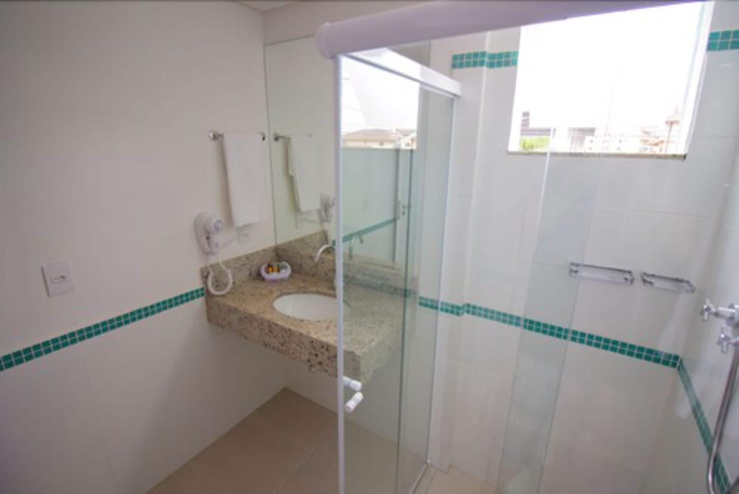 A bathroom with a glass-enclosed shower, a sink with a granite countertop, and a mirror above the sink.