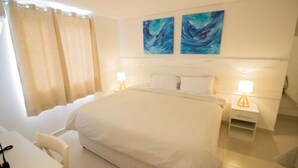 Een hotelkamer met een groot bed, twee nachtkastjes met lampen, een bureau en een stoel.