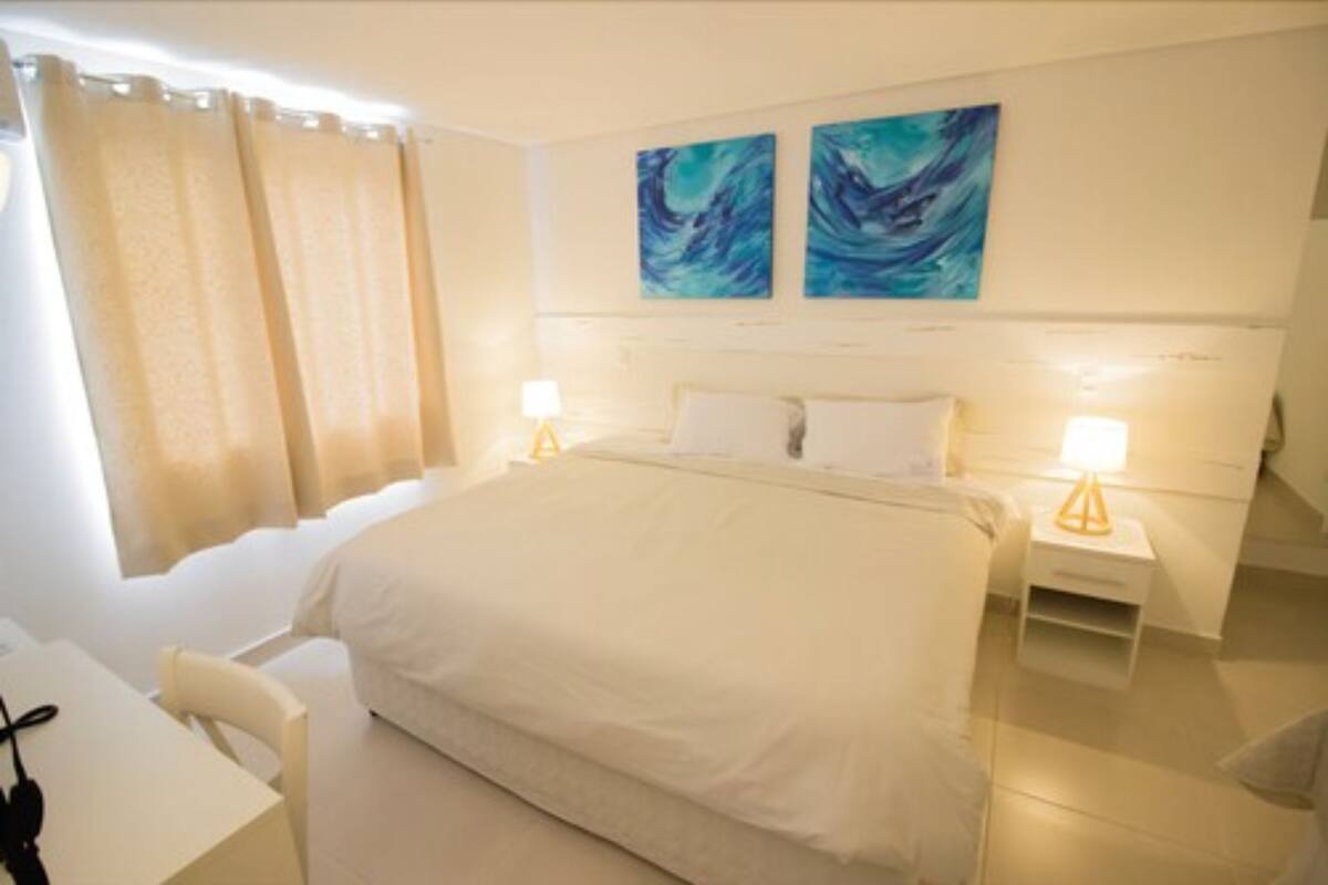 Ein Hotelzimmer mit einem großen Bett, zwei Nachttischen mit Lampen, einem Schreibtisch und einem Sessel.