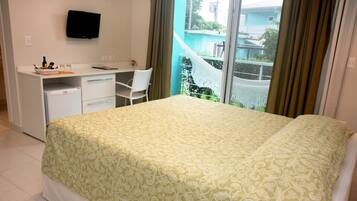 A hotel room with a bed, a desk, a chair, a refrigerator, and a TV on the wall.