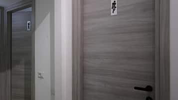 Un pasillo con puertas, una de ellas con el letrero de un baño.