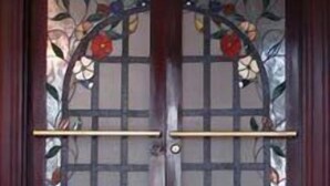 A double wooden door with a glass panel featuring a floral design. - Hotel Príncipe (Tulua)