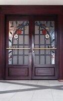 Puerta doble de madera con un panel de vidrio con diseño floral.