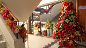 A staircase with red and gold decorations, a 'BIENVENIDO' sign, and a view of the outside through large windows. - Hotel Príncipe (Tulua)