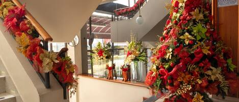 A staircase with red and gold decorations, a 'BIENVENIDO' sign, and a view of the outside through large windows.